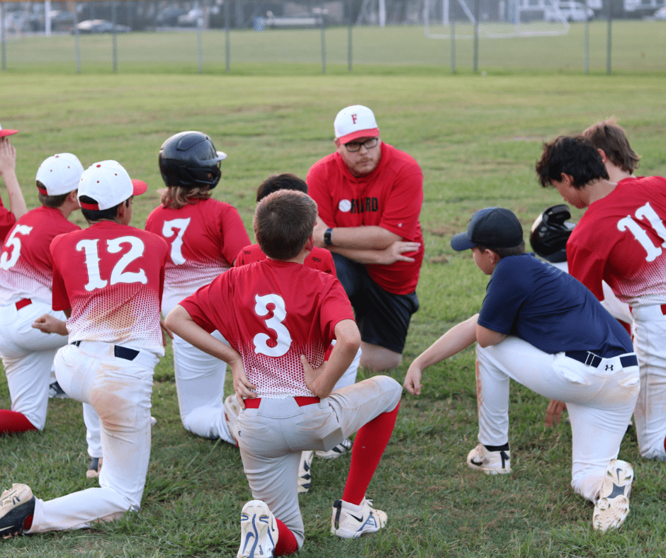 Forward Baseball Forward Athletics Club Boys Baseball Team Kneeling Around Coach Johnson for a Pep Talk During a Baseball Game.